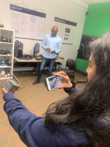 student holds merge smart phone in front of a merge cube AR block. Phone shows an AR beating heart.